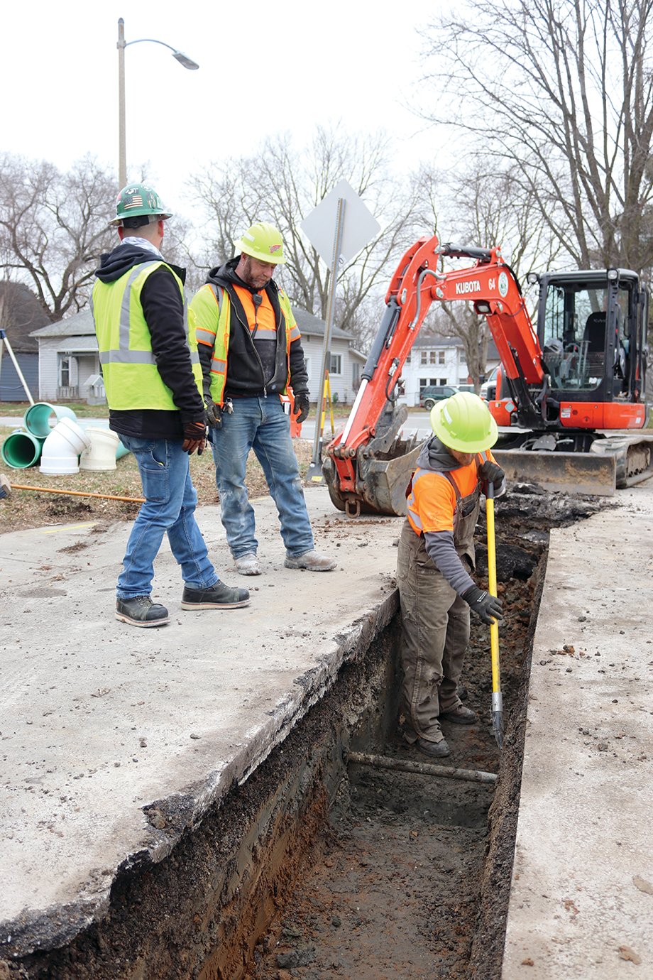 "Low man" Ed McGaughey digs carefully by hand around a retired gas pipe underneath Circle Drive Monday while stormwater foreman Chris Moore and Mick Selleck discuss the next step in the area's drainage improvement efforts.